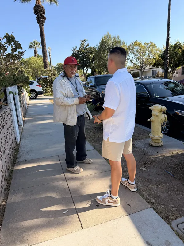 Alfredo Rodriguez talking with a resident on a neighborhood sidewalk