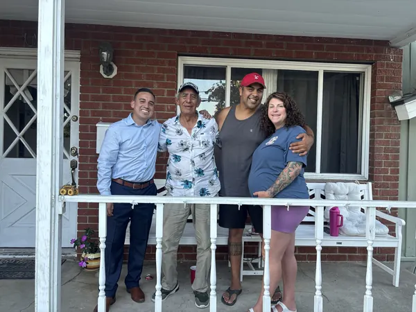 Alfredo Rodriguez with a family on their front porch