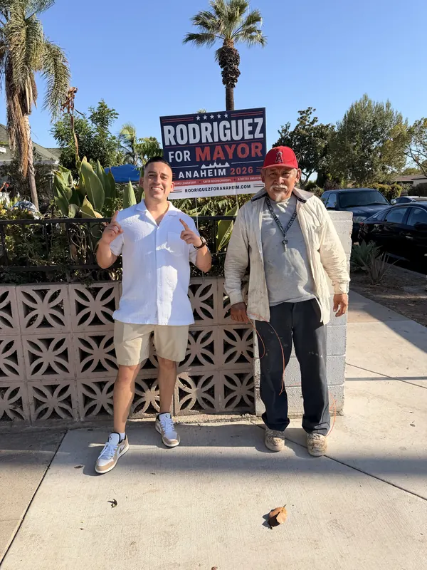 Alfredo Rodriguez with a resident next to a campaign yard sign